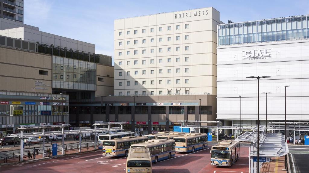 a parking lot with buses parked in front of a building at JR-East Hotel Mets Yokohama Tsurumi in Yokohama