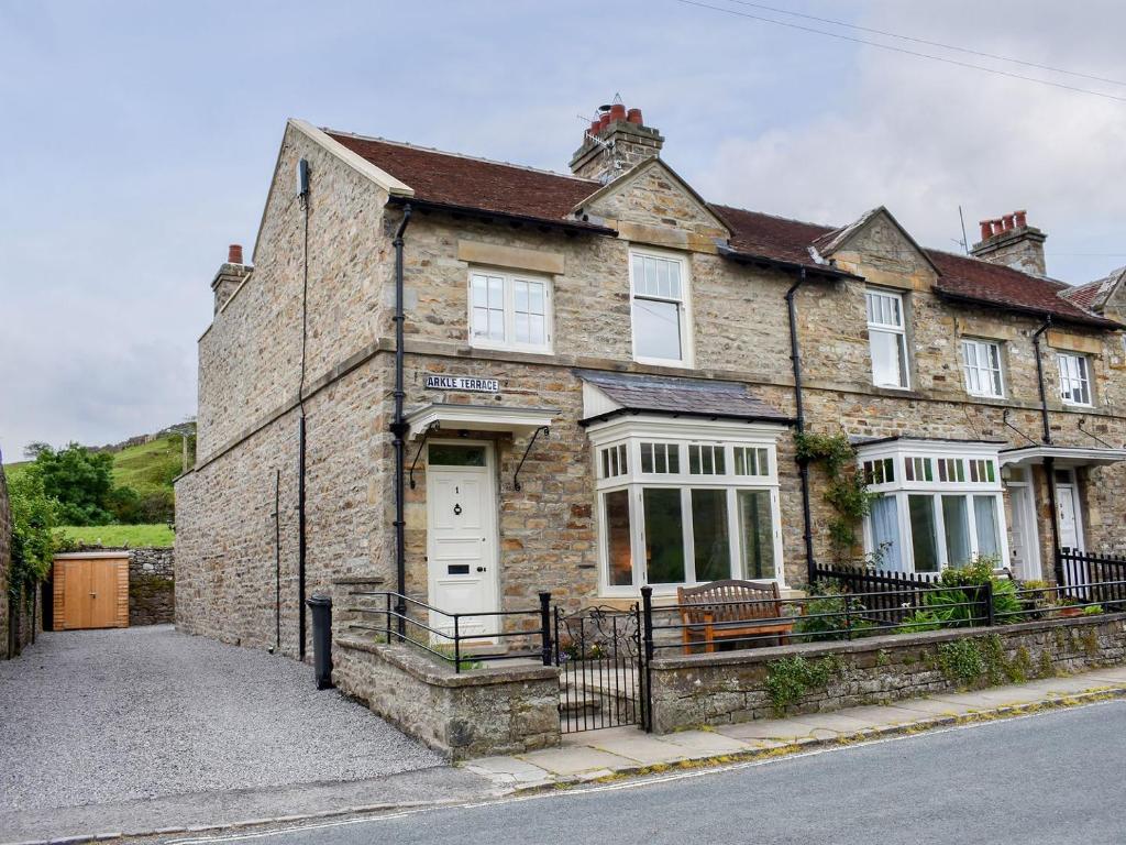 an old brick house with a white door at Arkle Terrace in Reeth