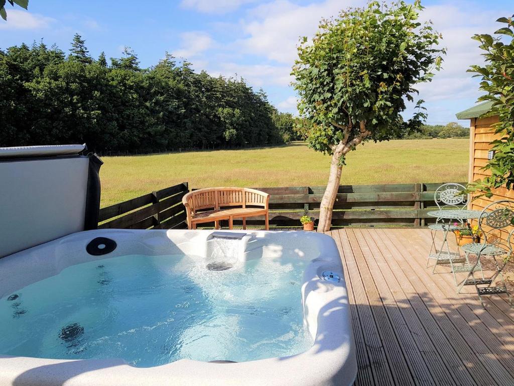a hot tub on a deck with a table and a bench at Trebor Cottage in Annan
