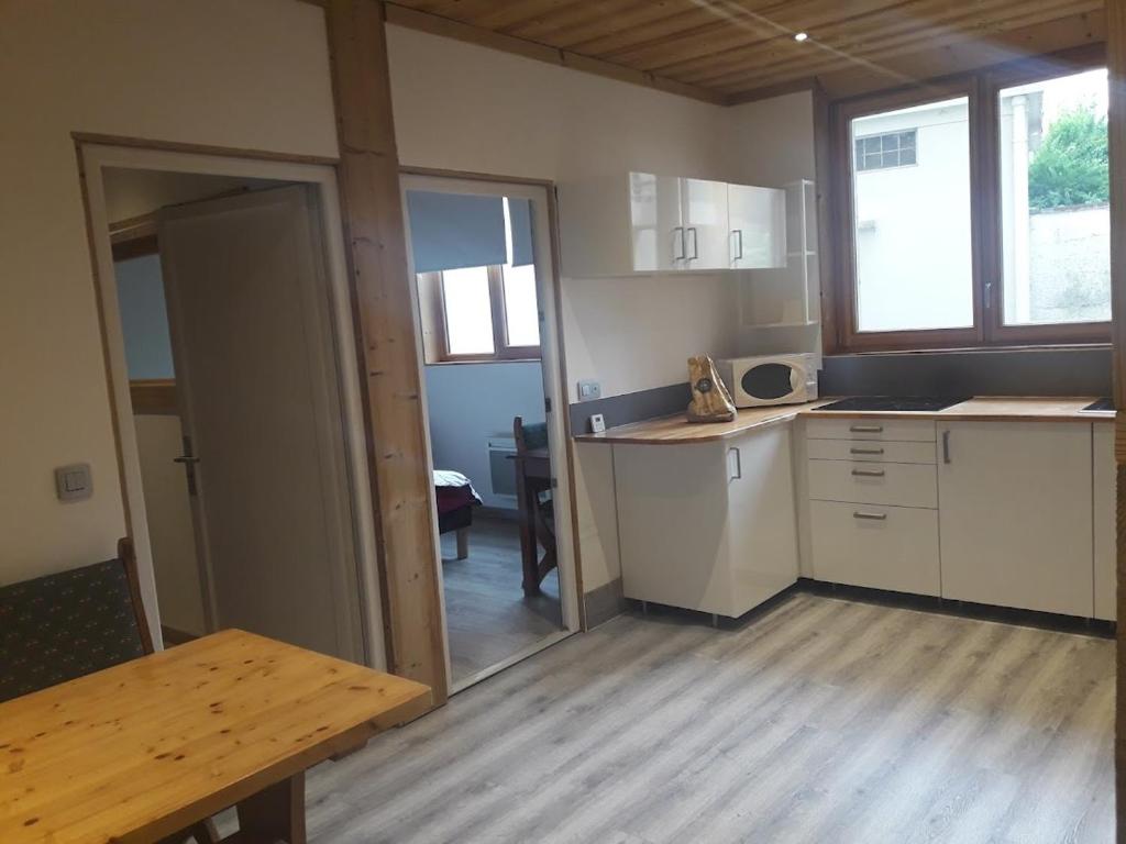une cuisine avec des placards blancs et une table en bois dans l'établissement COTTAGE 1 in the city, à Chambéry