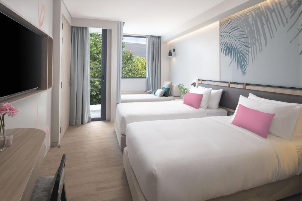 ein Hotelzimmer mit 2 Betten und einem Flachbild-TV in der Unterkunft JonoX Phuket Karon Hotel in Karon Beach