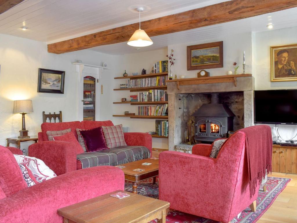 a living room with red chairs and a fireplace at Cam Cottage in Kettlewell