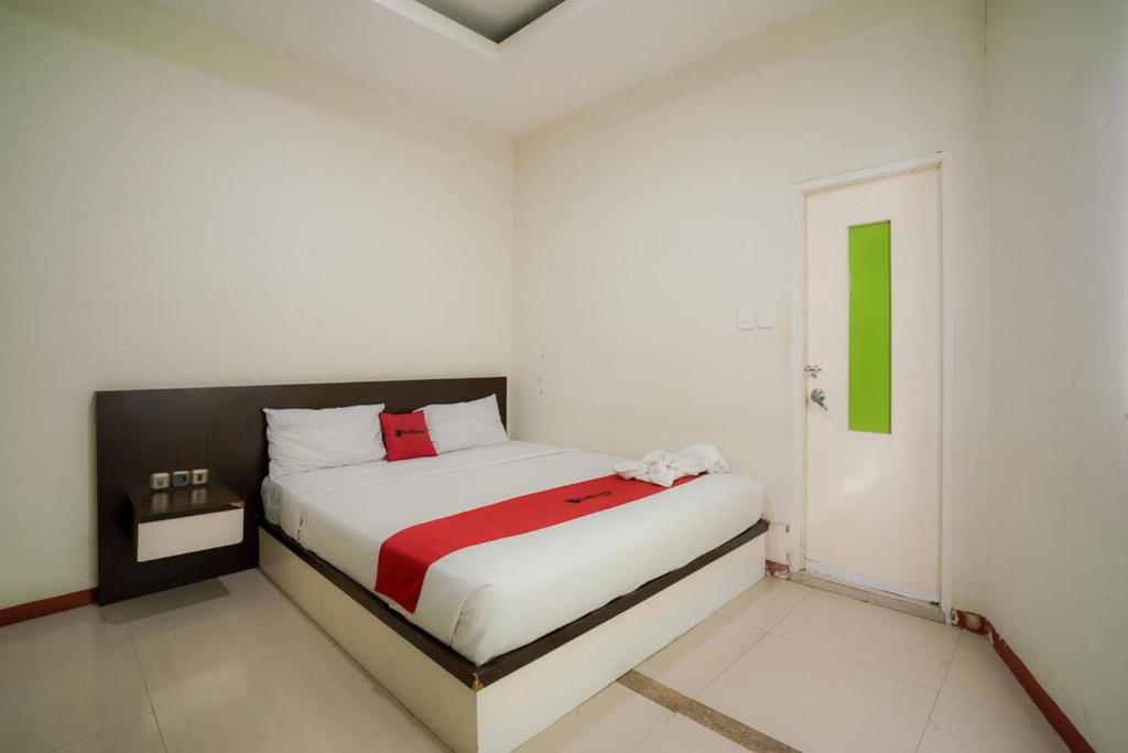 a white bedroom with a bed with a red blanket at RedDoorz near Pantai Pede in Labuan Bajo