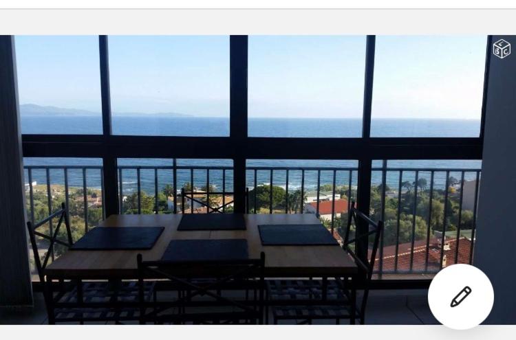 a table and chairs in front of a large window at Appartement vue Mer Sanguinaires à 5min des plages in Ajaccio