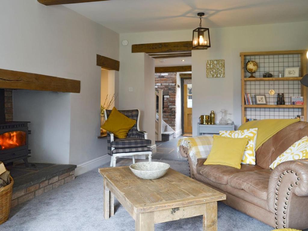 Grace Cottage في Umberleigh Bridge: غرفة معيشة مع أريكة ومدفأة