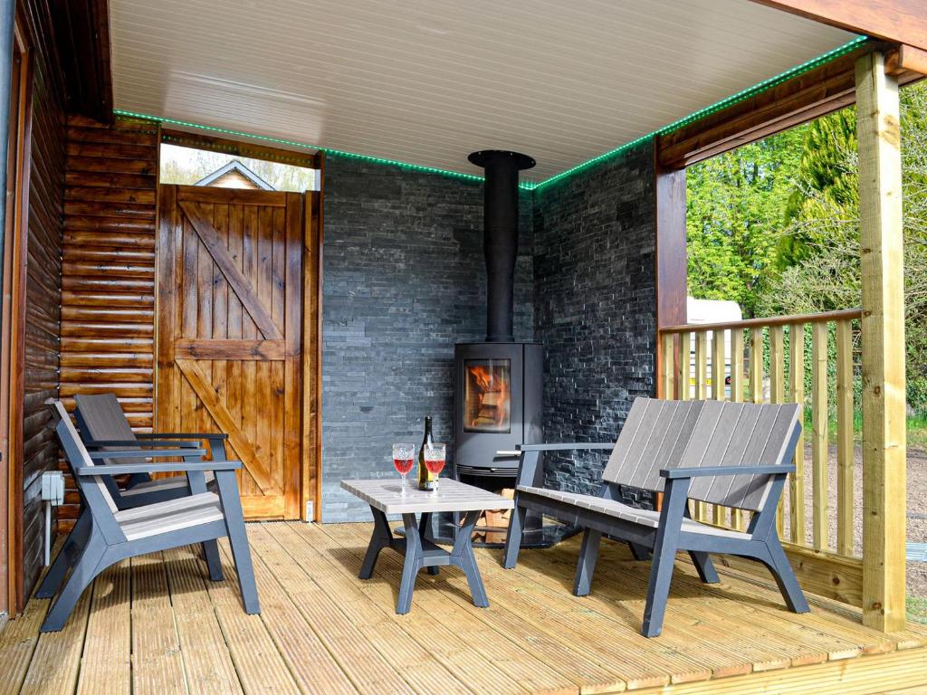 a deck with two chairs and a table and a stove at The Tranquil Orchard - Woodpecker-uk31339 in Mouswald