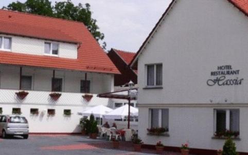un edificio blanco con techo rojo y un edificio con coche en Hotel Restaurant Hassia, en Frielendorf