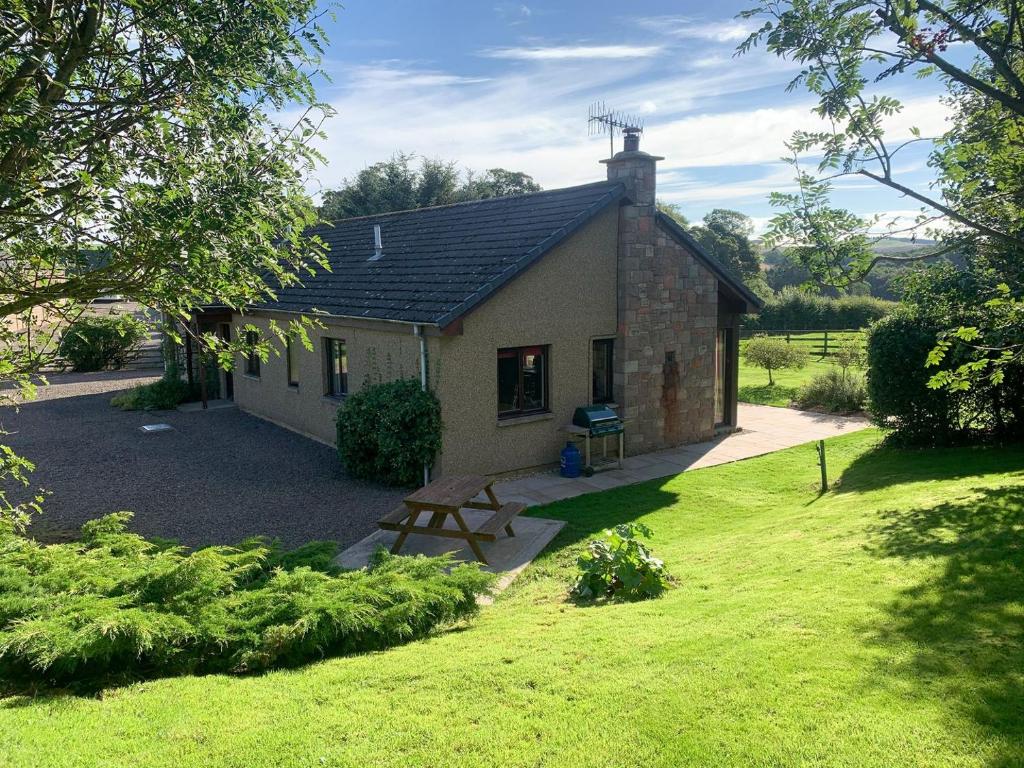 ein kleines Haus mit einem Picknicktisch im Hof in der Unterkunft Harelaw Brae in Grantshouse