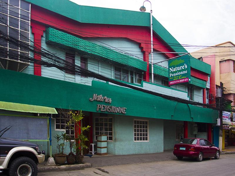 a green and red building with a parking garage at Nature's Pensionne House in Cagayan de Oro