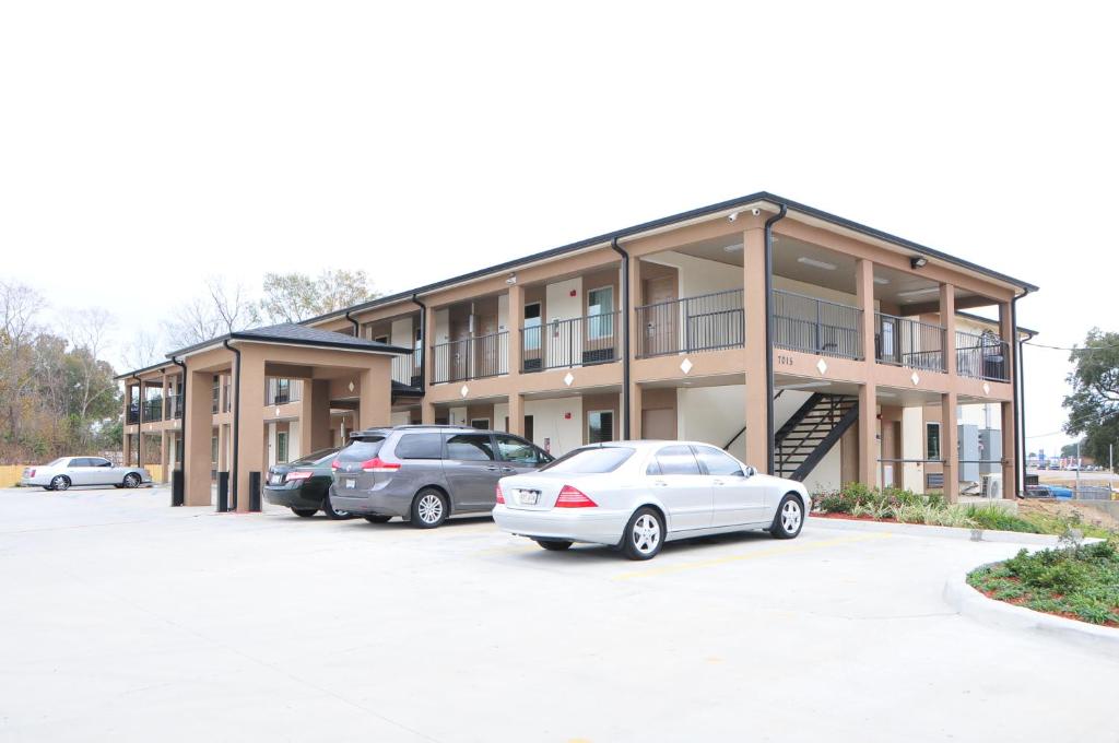 un edificio con due auto parcheggiate in un parcheggio di Paradise Inn & Suites a Baton Rouge