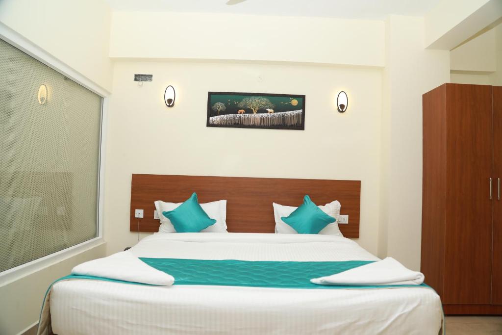 a bedroom with a large bed with blue pillows at Hotel Royal Chola in Kanchipuram
