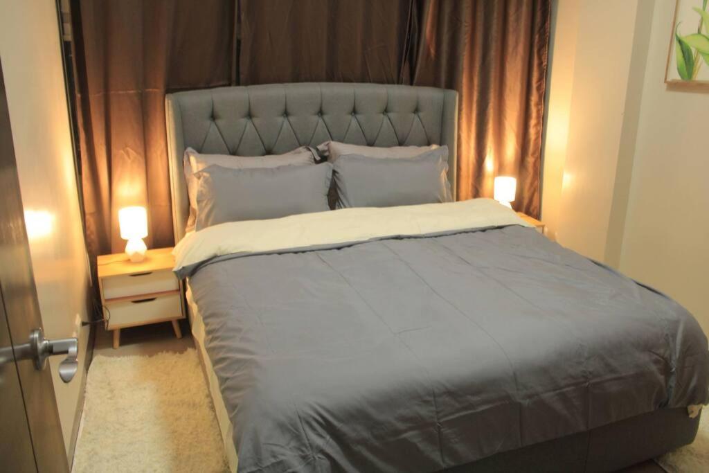 ein Schlafzimmer mit einem großen Bett mit zwei Lampen auf einem Nachttisch in der Unterkunft A2J Luxury 1BR Suite Near Venice Mall BGC Taguig in Manila