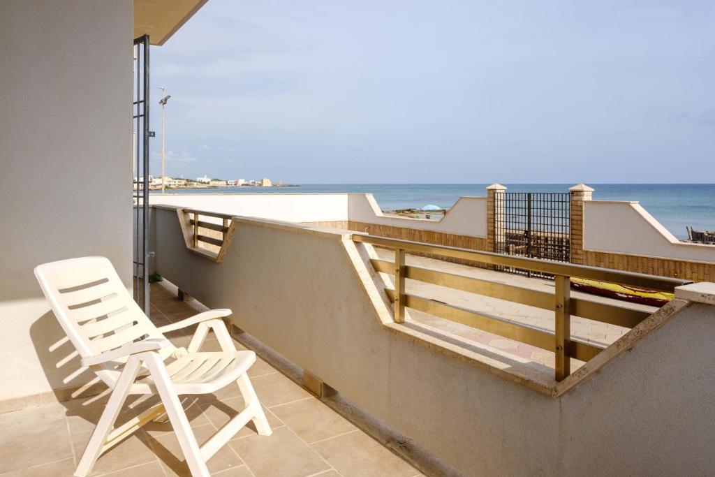 ein weißer Stuhl auf einem Balkon mit Blick auf den Strand in der Unterkunft Casa Vacanza Maria in Casalabate