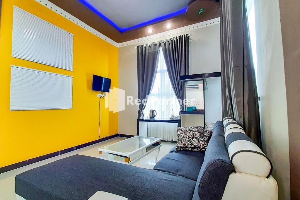 a living room with a blue couch and yellow walls at MT Syariah Homestay Kerinci RedPartner in Pondokpematangtanah