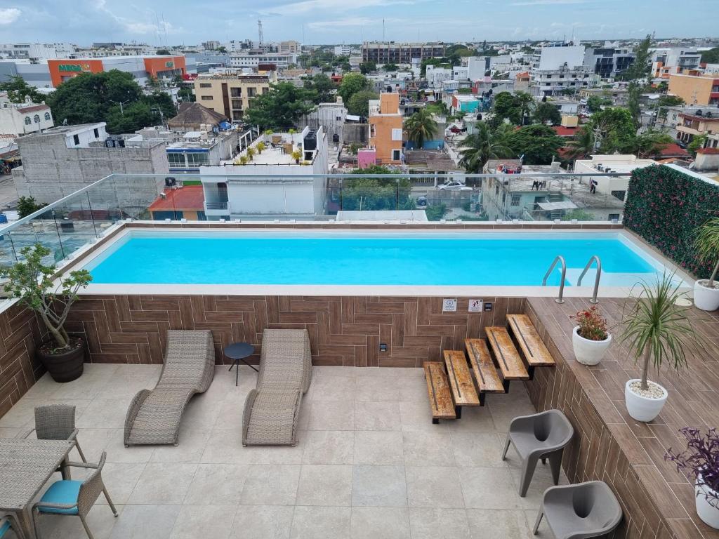 a swimming pool on top of a building with chairs at Cozy Studio with WiFi & Netflix in Playa del Carmen