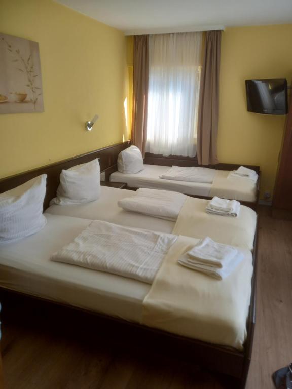 ein Hotelzimmer mit 3 Betten und einem Fenster in der Unterkunft Hotel Wiesbadener Hof in Stuttgart