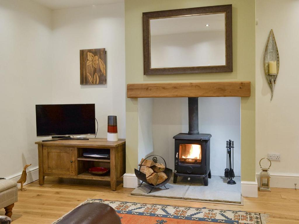 a living room with a fireplace and a tv at Riverholme in Bassenthwaite