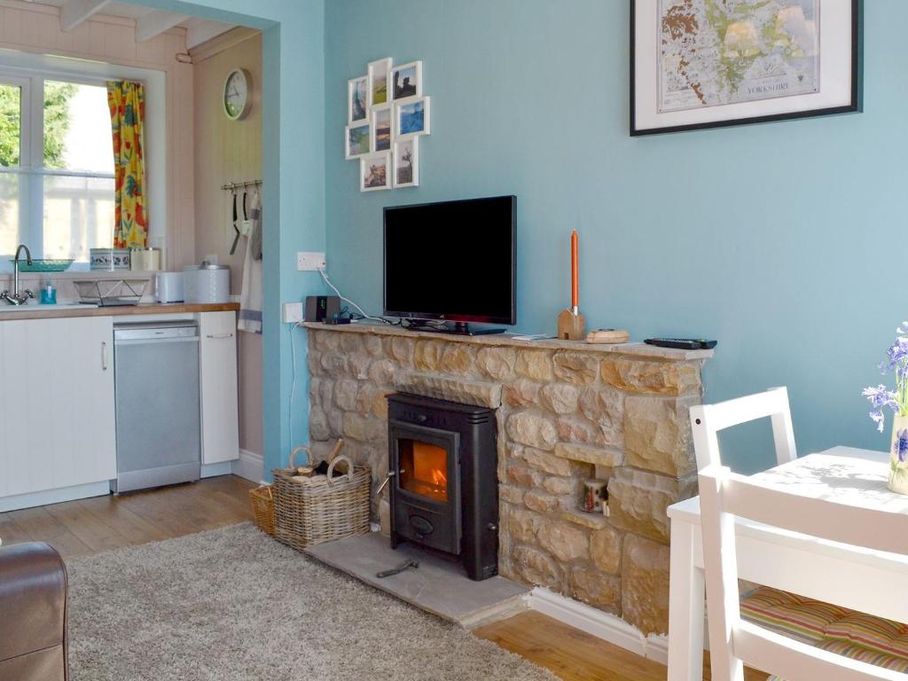 a living room with a stone fireplace with a tv on top at Crown Courtyard Cottage in Grewelthorpe