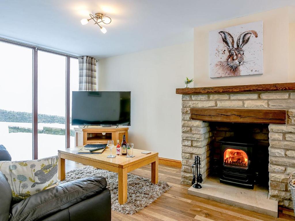 a living room with a fireplace and a television at Woodlands Clough - Uk32387 in Dunford Bridge