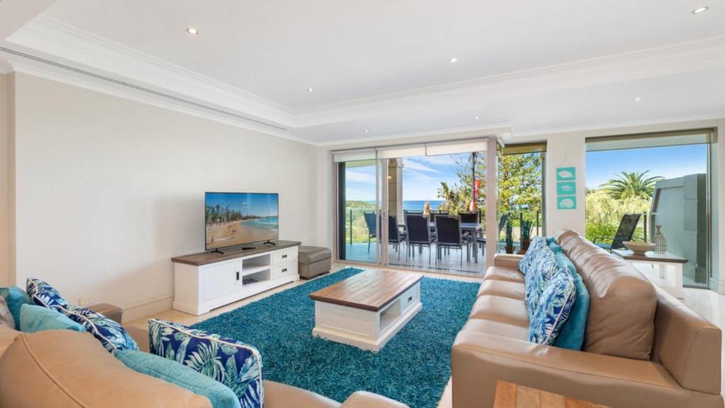 a living room with a couch and a tv at Unit 18 - 3 Bed Part Ocean View in Terrigal