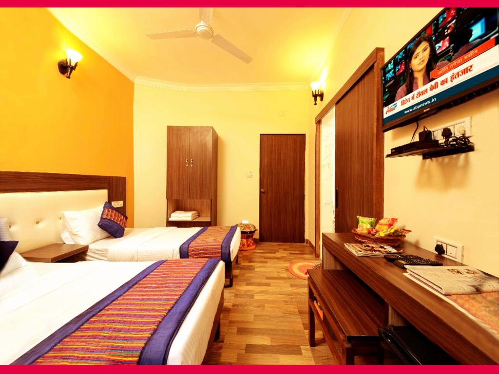 a hotel room with two beds and a desk at Taj Haveli Agra - 5 Minute Walking Distance from Taj Mahal Agra in Agra