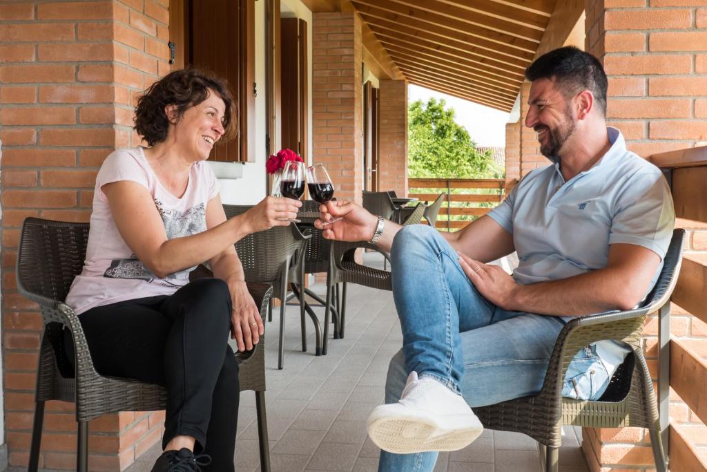 a man and woman sitting in chairs drinking wine at Albergo Diffuso Magredi in Vivaro