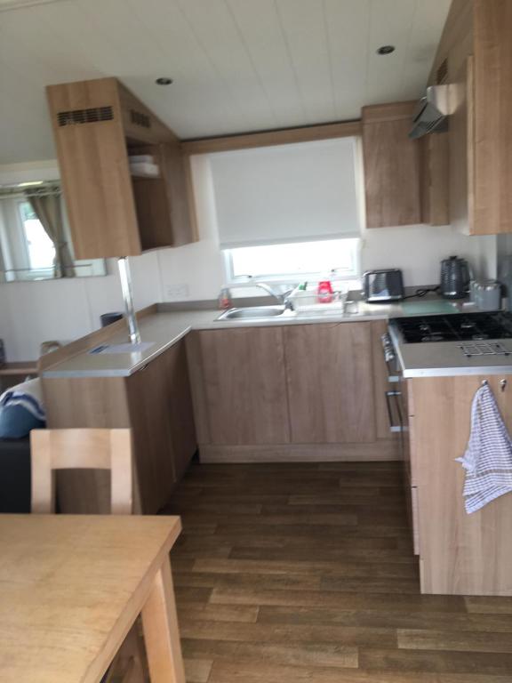 a small kitchen with wooden cabinets and a sink at Jacobs Retreat- Lido Beach- well behaved dogs welcome in Prestatyn