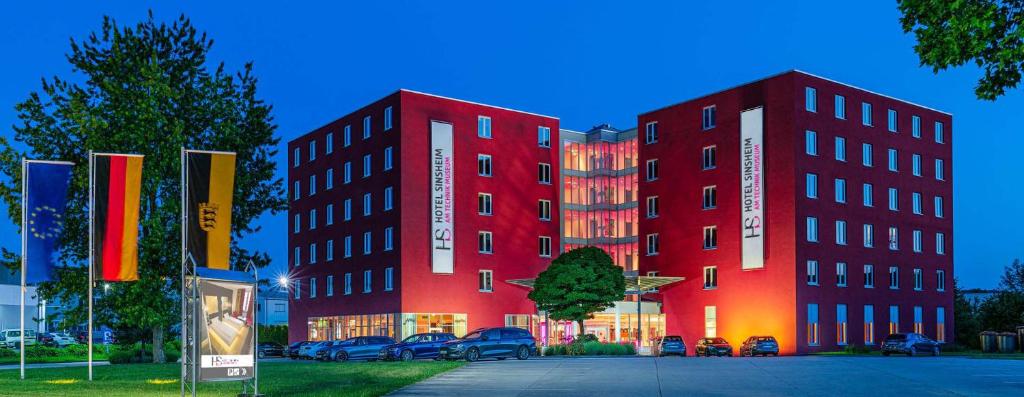 un bâtiment rouge avec des voitures garées devant lui dans l'établissement Hotel Sinsheim, à Sinsheim