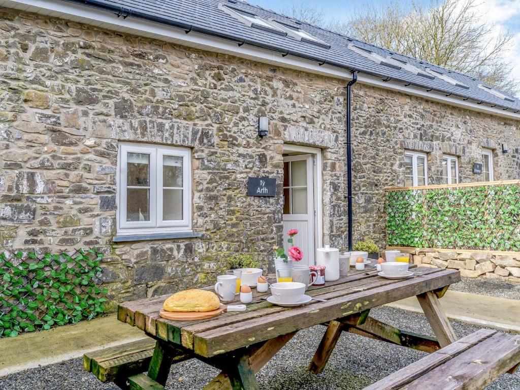 a wooden picnic table in front of a stone cottage at Ty Arth - Uk31652 in New Quay