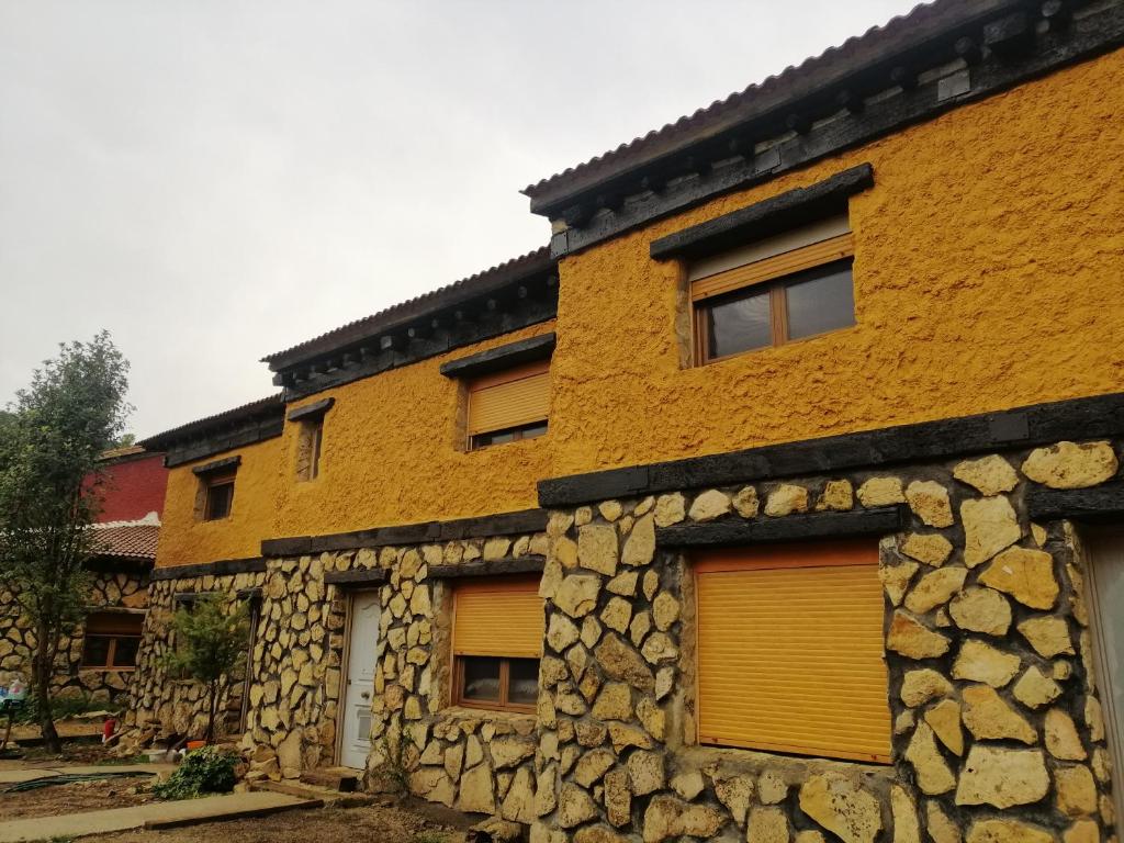 ein gelbes Gebäude mit einer Steinmauer in der Unterkunft Casas rurales La Trufa Madre Casa 3 in Vega del Cadorno