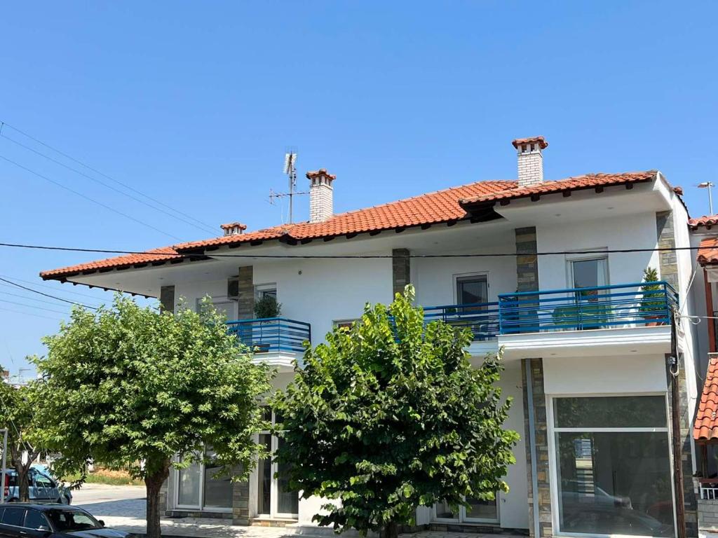 un bâtiment blanc avec des arbres devant lui dans l'établissement Vassilikos Apartment, à Flogita