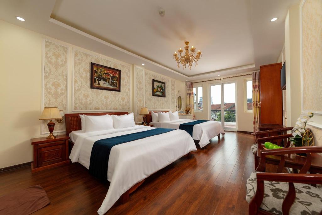 a hotel room with two beds and a chandelier at Hanoi Delica Hotel in Hanoi