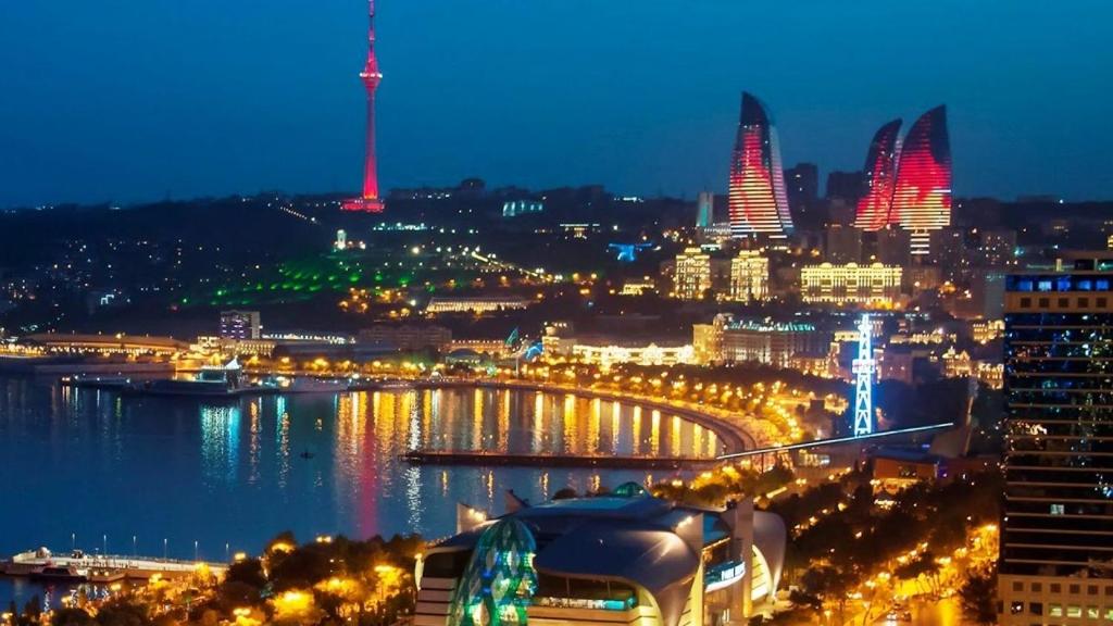 a city lit up at night with a river and buildings at Riviera Hotel in Baku