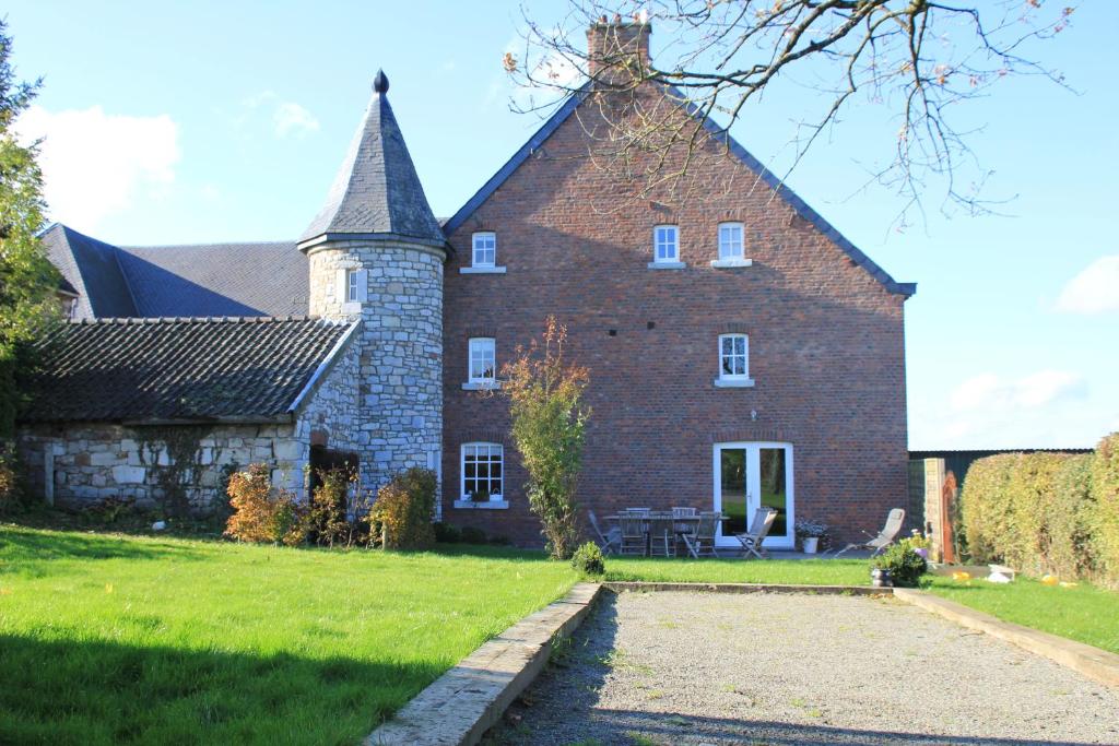 an old brick building with a spire on a yard at Gite des Comagnes in Limbourg