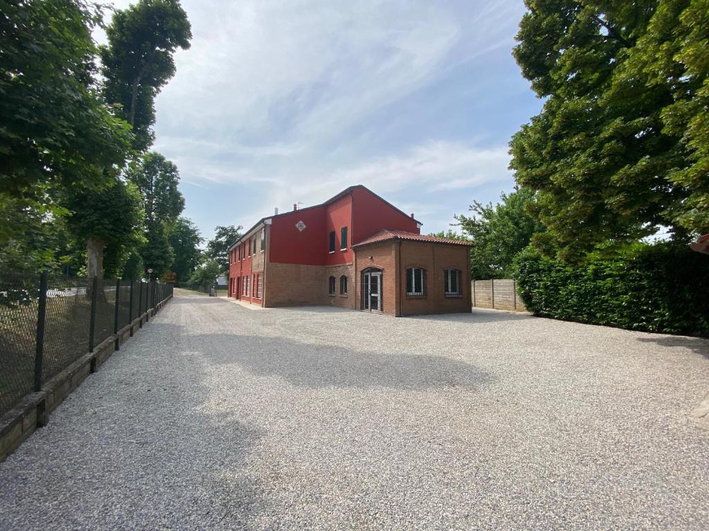 un edificio rojo en un camino de grava junto a una valla en Ca Rossa, en Bondeno