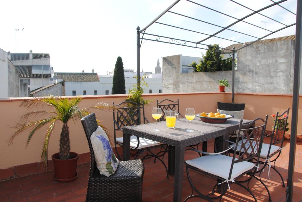 einen Tisch und Stühle auf einem Balkon mit Weingläsern in der Unterkunft Puerta San Esteban in Sevilla