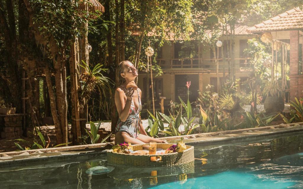 a woman sitting next to a swimming pool at Valley Village Phu Quoc in Phu Quoc