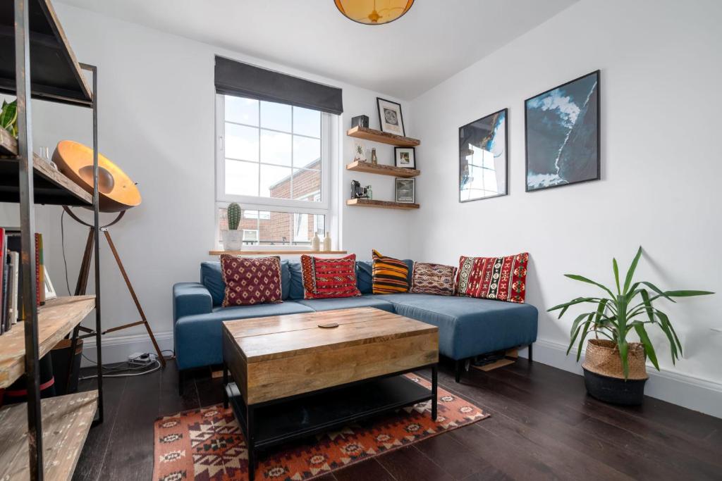 a living room with a blue couch and a table at GuestReady - Modern Chic in Homerton in London
