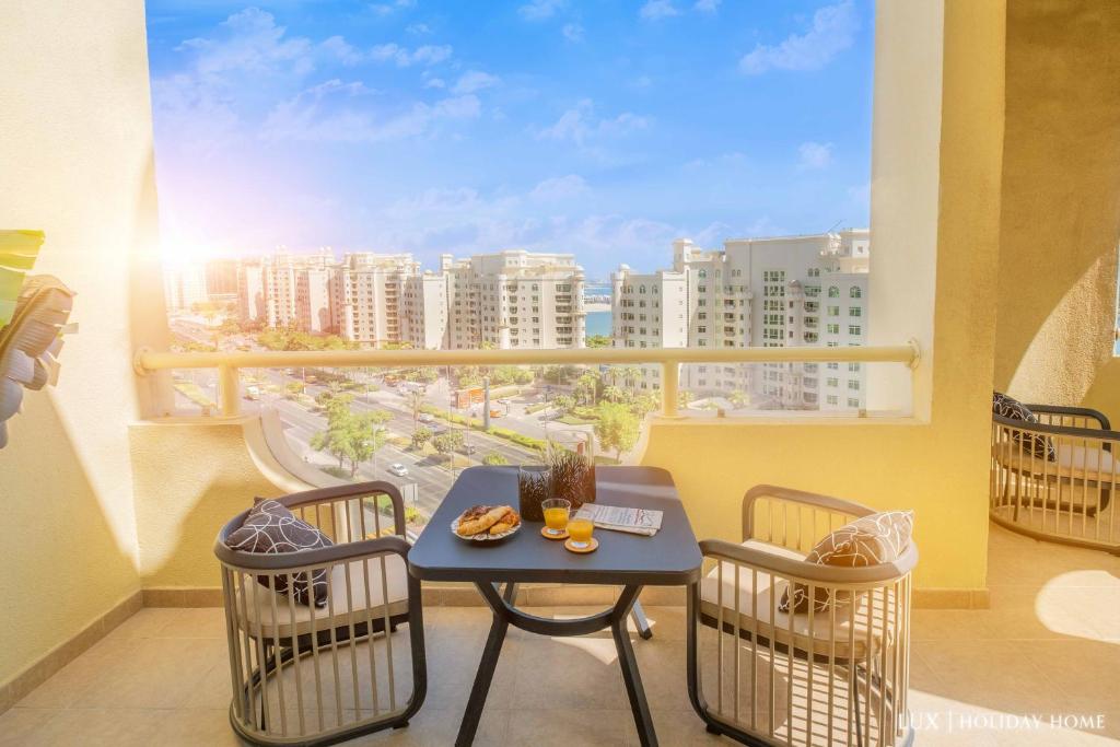 einen Balkon mit einem Tisch und Stühlen sowie Stadtblick in der Unterkunft LUX - The Shoreline Penthouse Suite in Dubai