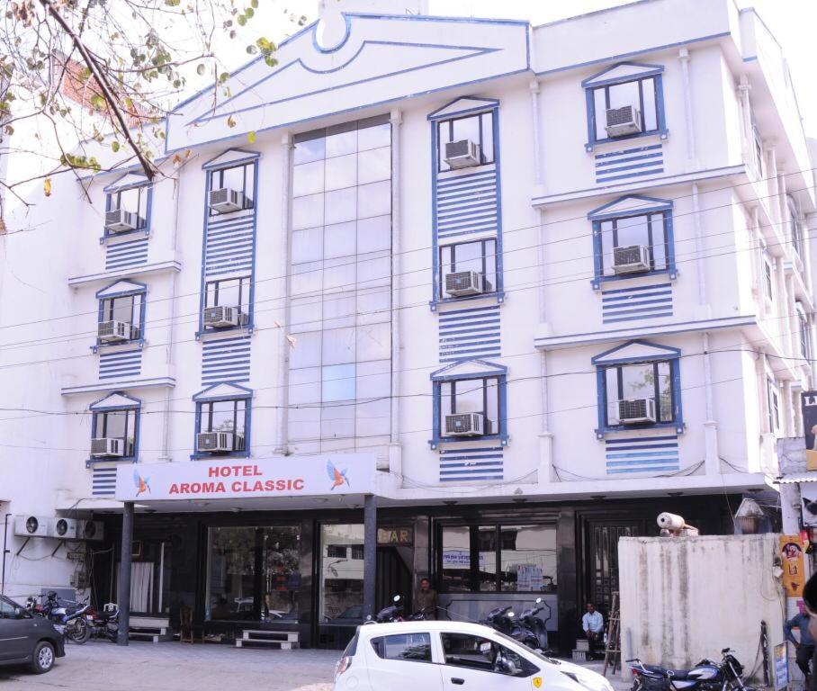 Hotel aroma classic في جايبور: مبنى أبيض فيه سيارة متوقفة أمامه
