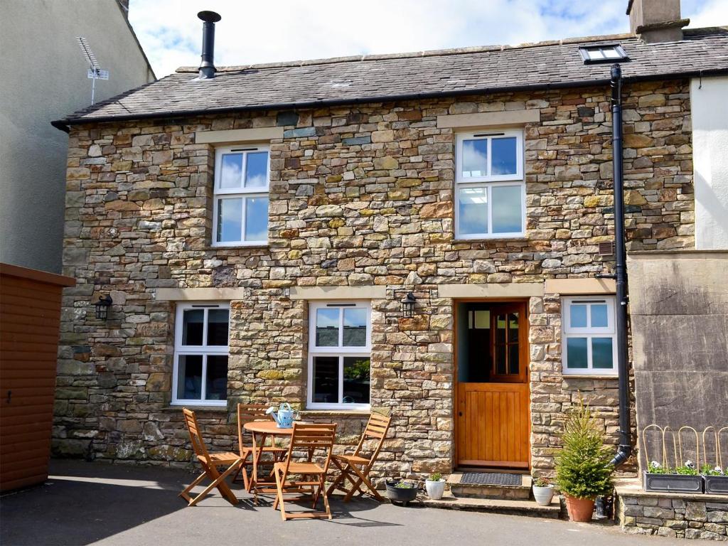 a stone cottage with a table and chairs in front of it at Keats Barn in Ireby