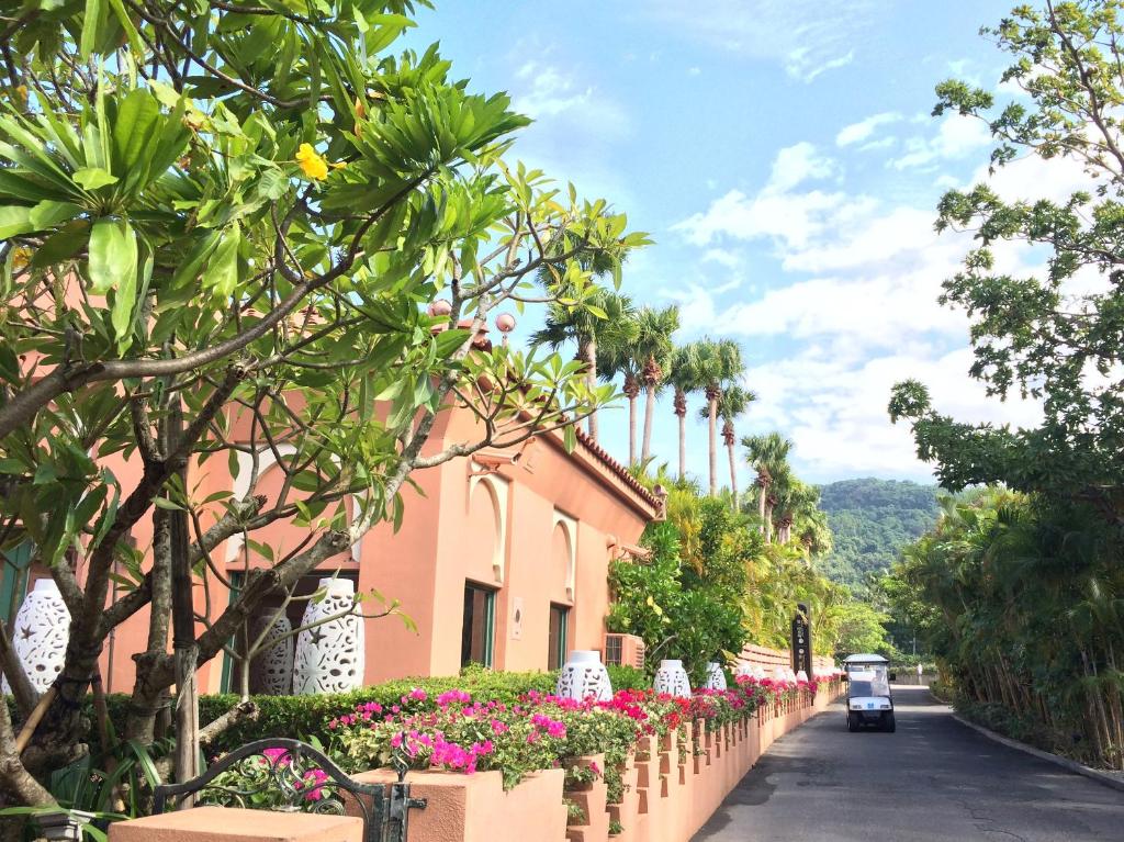 a car driving down a street next to a pink building at Kenting Amanda Hotel in Nanwan