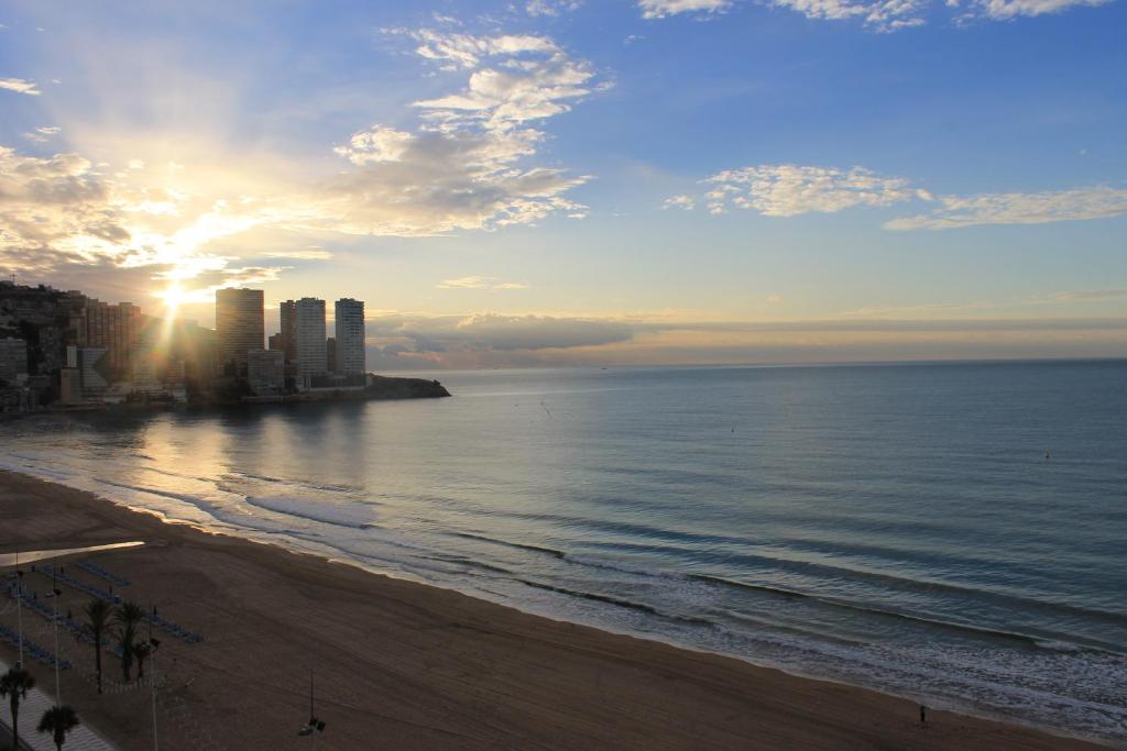 a view of a beach with the sun setting over the ocean at Les Dunes Comodoro in Benidorm