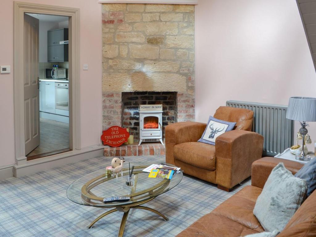 a living room with a glass table and a fireplace at The Old Telephone Exchange in Rothbury