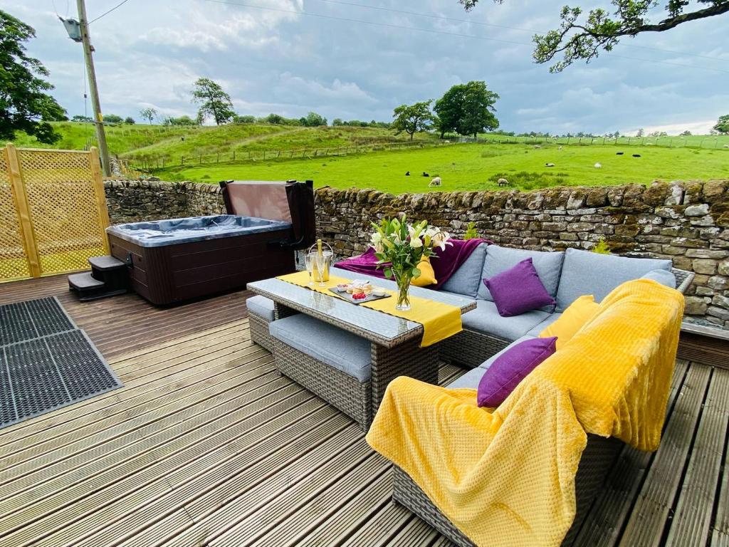 a patio with a couch and a table on a deck at Lily Rose Cottage in Gilsland