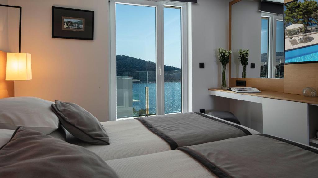 a bedroom with a bed and a large window at Royal Neptun Hotel in Dubrovnik