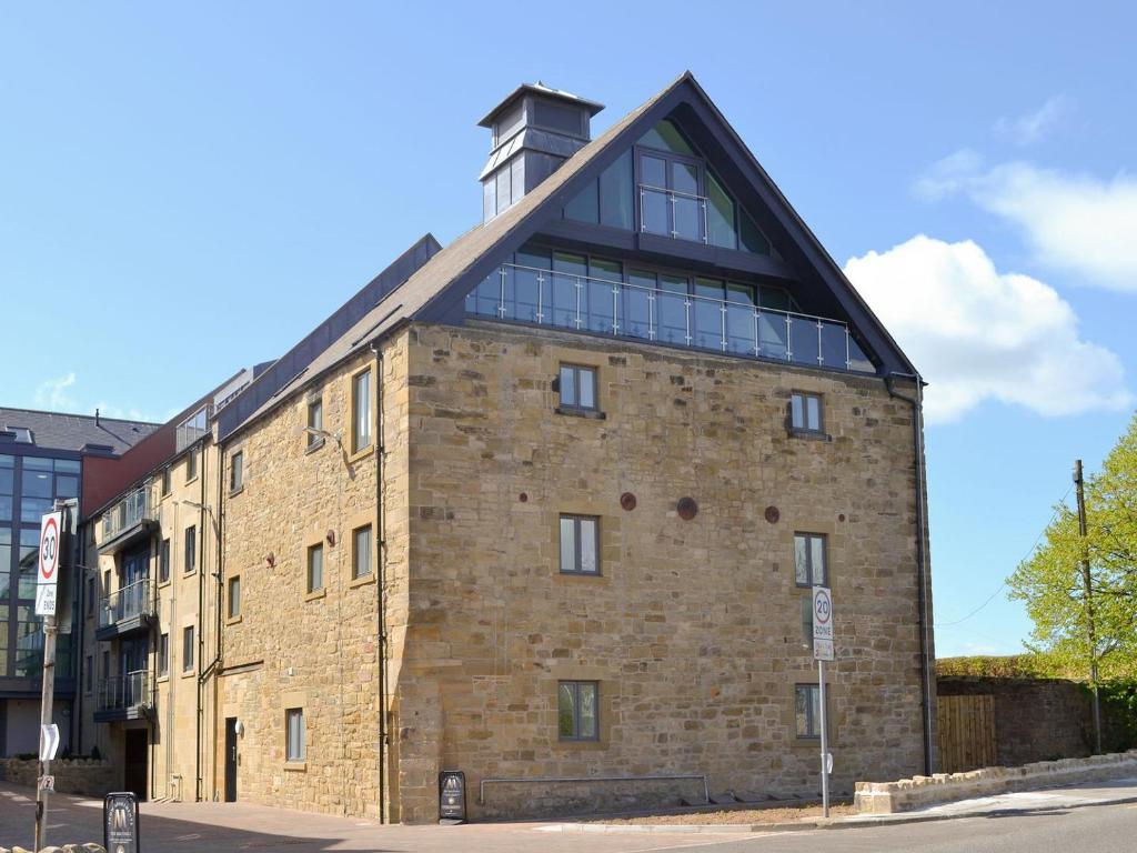 a large brick building with a clock tower on top at Alnwick Old Brewery Apartment in Alnwick