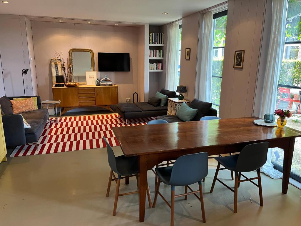 Una sala de estar con una mesa y sillas de madera. en Luxe tuinhuis nabij Amsterdam, en Oostzaan