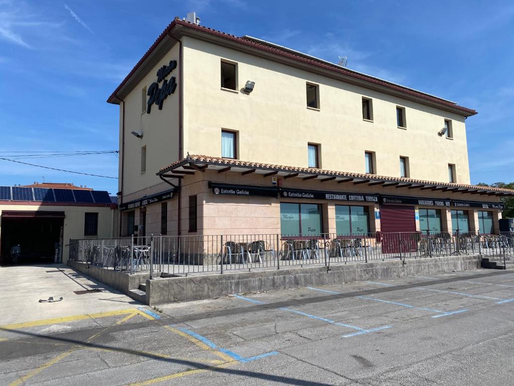 un bâtiment avec des tables et des chaises dans un parking dans l'établissement Hostal Meson Pepa, à Logroño