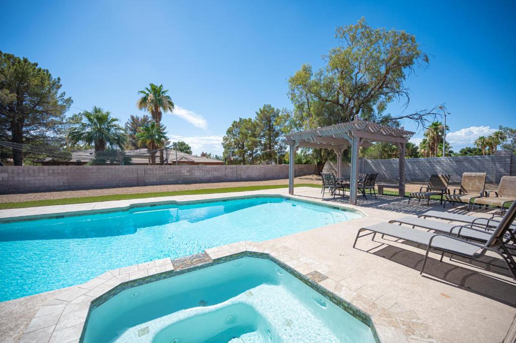 a swimming pool with two chairs and a umbrella at Luxury Home Near Las Vegas Strip and Airport. in Las Vegas